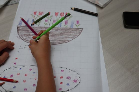 kadr na rysującą osobę, widać rękę, która trzyma kredki rysuje kwiatki