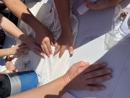 zbliżenie na ręce które dotykają tego co ukryte jest w bawełnianych woreczkach.