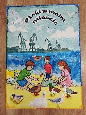 III miejsce klasa III z Otwartej Niepublicznej Szkoły Podstawowej nr 1 w Baninie Ptaki wśród 2 osób kucajacych na plaży, w tle żurawie portowe i lecące ptaki.