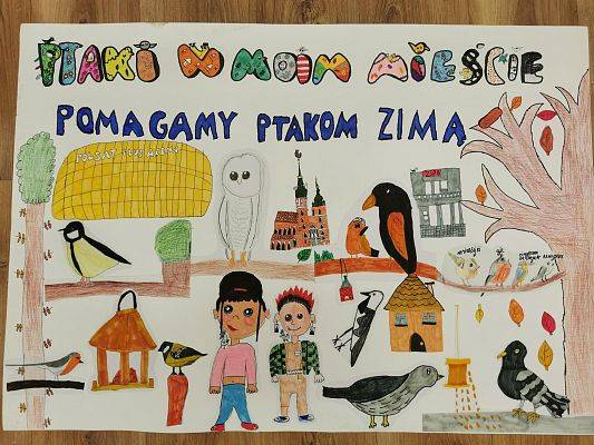 Wyróżnienie Klasa III ze świetlicy w Zespole Szkolno-Przedszkolnym nr 8 w Gdańsku Kolorowe ptaki na tle scenki w mieście, w tym żółtego stadionu, na górze napis pomagamy ptakom.